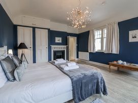 A bedroom with a bed and armchair at Holly Lodge in Aldeburgh