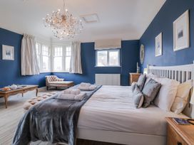 A bedroom with a bed, armchair, and table at Holly Lodge in Aldeburgh