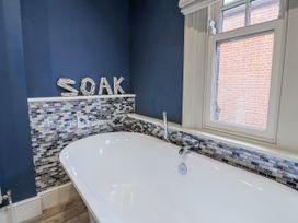A bathtub with a mosaic tile surround at Holly Lodge in Aldeburgh
