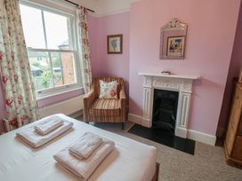 A bedroom with a bed and armchair at Lavender House, Aldeburgh