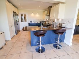 A kitchen with a countertop, sink, and bar stools at Seadrift in Dunwich Near Westleton