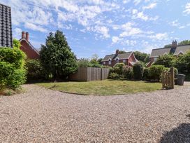 A garden with a gravel driveway and trees at Seadrift in Dunwich Near Westleton