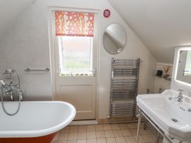 A bathroom with a bathtub, sink, towel rail and mirror at Mariners Cottage, King Street in Aldeburgh