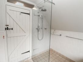 A shower area with a glass partition and a wooden door at Mariners Cottage, King Street in Aldeburgh