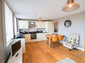A kitchen with cabinets and a dining table at The Hive, Southwold