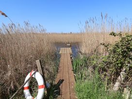 A dock with a lifebuoy and reeds at The Cart House in Sudbourne Near Orford