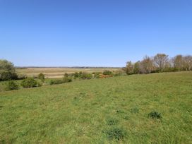 A grassy field with trees and a clear sky at The Cart House Sudbourne Near Orford