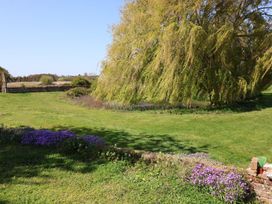 A garden with grass, flowers, and a tree at The Cart House Sudbourne Near Orford