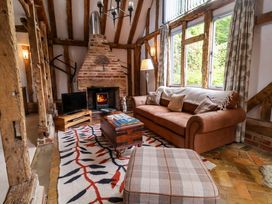 A living room with a sofa, television, and fireplace at Wassicks Cottage, Haughley