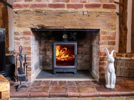 A fireplace with a wood stove and decorative items at Wassicks Cottage, Haughley