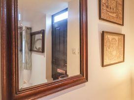 A hallway with a mirror and framed pictures at Pine Cottage in Woodbridge