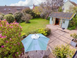 A garden with a green shed and patio furniture at Robert Sadler's Studio in Aldeburgh