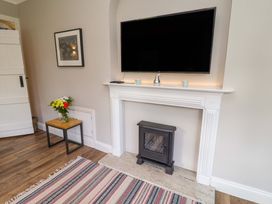 A living room with a television above a fireplace at The Round House in Easton near Framlingham