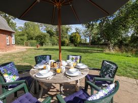 A dining table set with plates and drinks in the garden at The Round House in Easton near Framlingham