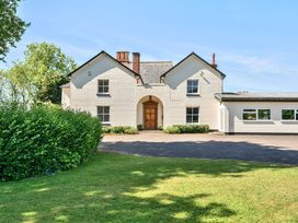 A white two-story house with a central wooden door and windows surrounded by greenery at Bedingfield House nr Debenham Debenham 