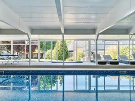 An indoor swimming pool with lounge chairs and a ping pong table behind glass windows at Bedingfield House nr Debenham Debenham