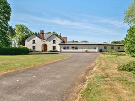 A white house with a wooden door and multiple windows surrounded by grass and trees at Bedingfield House nr Debenham Debenham