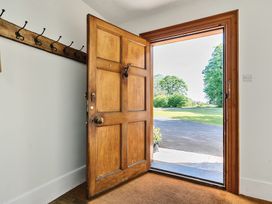 An open wooden front door showing a driveway and lawn outside with coat hooks on the interior wall at Bedingfield House nr Debenham Debenham