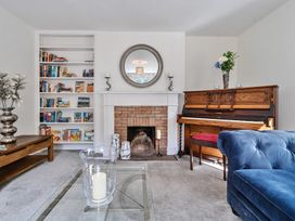 A living room with a brick fireplace a wooden piano a blue sofa and a bookshelf at Bedingfield House nr Debenham