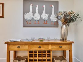 A wooden console table with drawers and baskets below a painting of five white geese at Bedingfield House nr Debenham
