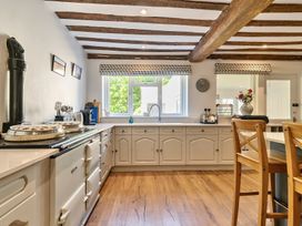 A kitchen with wooden ceiling beams white cabinets a window wooden chairs and an oven at Bedingfield House nr Debenham Debenham