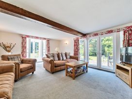 A living room with brown sofas a wooden coffee table and glass doors with red and white curtains at Bedingfield House nr Debenham Debenham