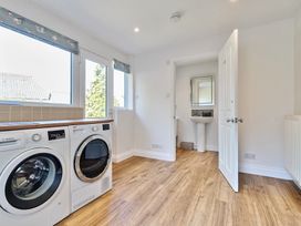 A laundry room with washing machine, dryer, sink, and wooden floor at Bedingfield House nr Debenham in Debenham