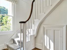 A staircase with carpeted steps and a wooden handrail next to a window and a small door under the stairs at Bedingfield House nr Debenham Debenham