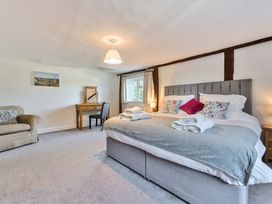 A bedroom with a large bed with folded towels bedside tables a window a desk with a chair and an armchair at Bedingfield House nr Debenham Debenham