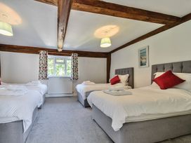 A bedroom with three single beds each with red pillows and white linens at Bedingfield House nr Debenham Debenham