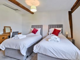 A bedroom with two single beds with white bedding and red pillows a wooden dresser with a mirror and lamp at Bedingfield House nr Debenham Debenham