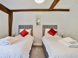 A bedroom with two single beds each with a red pillow and folded towels on a grey carpet at Bedingfield House nr Debenham Debenham
