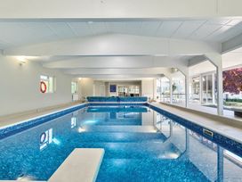 An indoor swimming pool with a diving board and windows showing an outdoor area at Bedingfield House nr Debenham