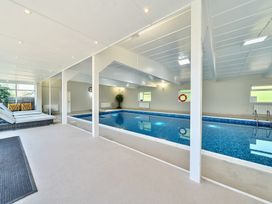 An indoor swimming pool with lounge chairs and a table near windows at Bedingfield House nr Debenham Debenham