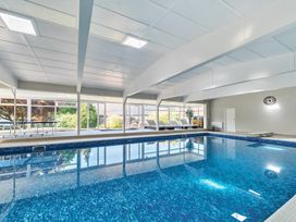 An indoor swimming pool with lounge chairs and a clock on the wall at Bedingfield House nr Debenham Debenham