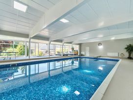 An indoor swimming pool with lounge chairs and plants at Bedingfield House nr Debenham Debenham