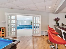 A recreational room with red bar stools a pool table and glass doors leading to an indoor swimming pool at Bedingfield House nr Debenham Debenham