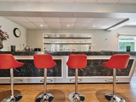 A bar area with four red bar stools wooden floor and glassware on shelves behind the counter at Bedingfield House nr Debenham Debenham