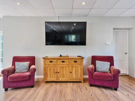 A living room with two red armchairs and a wooden cabinet beneath a wall-mounted television at Bedingfield House nr Debenham Debenham
