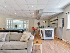A room with a gray sofa, a bar counter with red stools, a pool table, and shelves with glassware at Bedingfield House nr Debenham Debenham