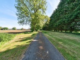 A paved pathway with green grass on both sides and trees lining the path at Bedingfield House nr Debenham Debenham