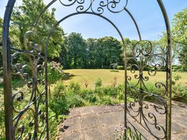 A garden with a metal gate leading to a grass lawn and trees at Bedingfield House nr Debenham in Debenham