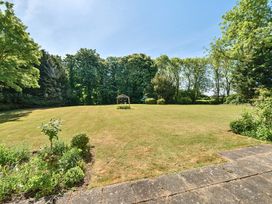 A large grassy garden with a metal gazebo structure in the center surrounded by trees and flower beds at Bedingfield House nr Debenham Debenham 