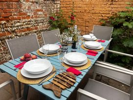 A dining table set with plates and glasses in an outdoor dining area at Seaflower, Aldeburgh