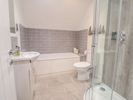 A bathroom with a sink, bathtub, toilet, and shower at Corner Cottage, Thorpeness