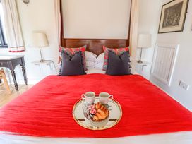 A bedroom with a red blanket and breakfast items at Fishpond House, Sotherton