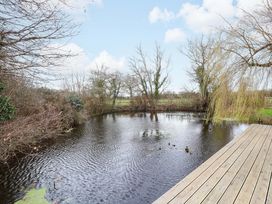 A pond surrounded by trees and wooden decking at Fishpond House, Sotherton Halesworth