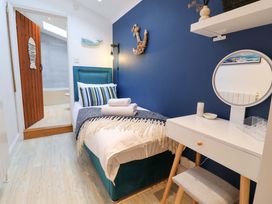 A bedroom with a bed and a desk at The Smokehouse Cottage in Southwold