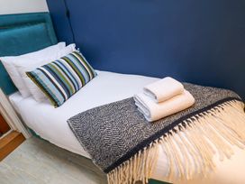 A bed with a striped pillow and two towels at The Smokehouse Cottage in Southwold