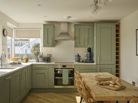 A kitchen with cabinets, oven, sink and dining table at Harbour Lights in Southwold